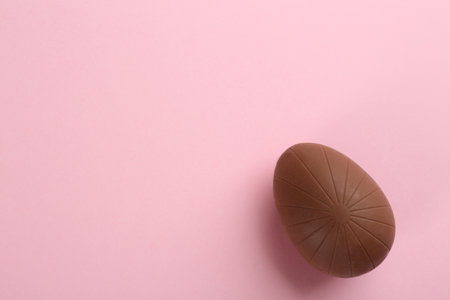 Sweet chocolate egg on pink background, top view. Space for textの写真素材
