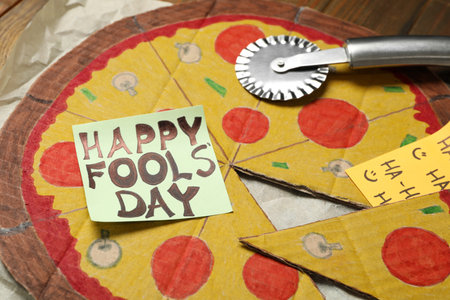 Cardboard pizza and Happy Fools' Day note on wooden table, closeupの写真素材