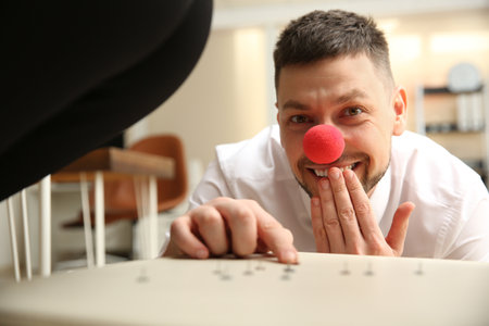 Man putting pins on chair while his colleague sitting down in office, closeup. funny jokeの写真素材