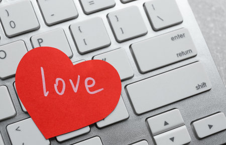 Paper heart with word LOVE on laptop, closeupの写真素材