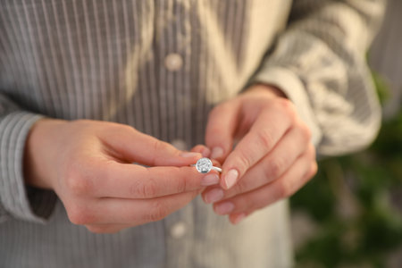 Woman holding wedding ring indoors, closeup. Divorce conceptの写真素材