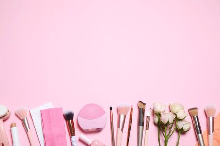 Different makeup brushes, accessories and flowers on pink background, flat lay. Space for textの写真素材