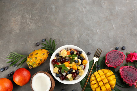 Flat lay composition with delicious exotic fruit salad on gray table. Space for textの写真素材