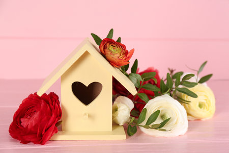 Stylish bird house and fresh eustoma on pink wooden tableの写真素材
