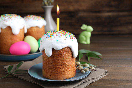 Easter cake with burning candle on wooden table
