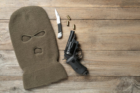 Flat lay composition with balaclava and weapons on wooden table, space for textの写真素材