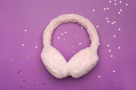 Stylish winter earmuffs and confetti on purple background, flat layの写真素材