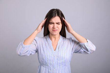 Portrait of stressed young woman on gray backgroundの写真素材
