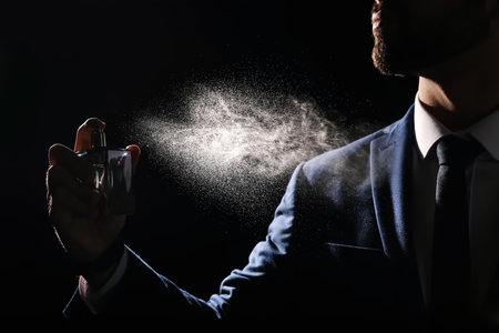 Man spraying luxury perfume on black background, closeupの写真素材