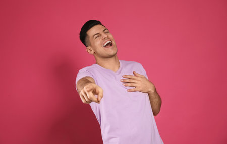 Handsome man laughing on maroon background. funny jokeの写真素材