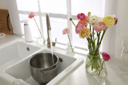 Light kitchen decorated with beautiful fresh ranunculus flowersの写真素材