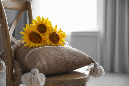 Bouquet of beautiful sunflowers and cushion on chair indoorsの写真素材
