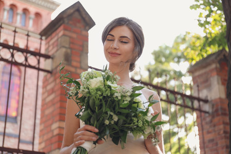 Gorgeous bride in beautiful wedding dress with bouquet near churchの写真素材