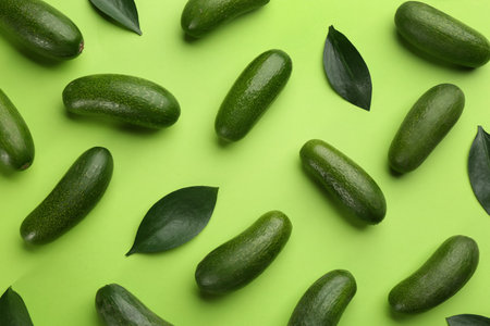 Whole seedless avocados with leaves on green background, flat layの写真素材