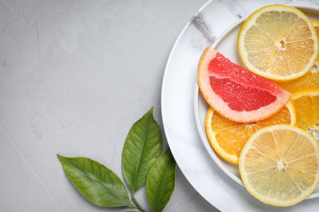 Cut citrus fruits and leaves on grey background, flat lay. Space for textの写真素材