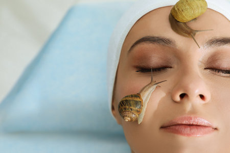 Young woman receiving snail facial massage in spa salon, closeup. Space for textの写真素材