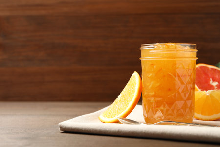 Delicious orange marmalade and fresh fruits on wooden table. Space for textの写真素材