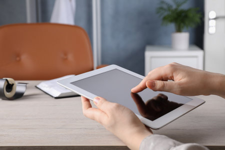 Woman using modern tablet at workplace indoors, closeupの写真素材