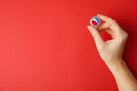 MYKOLAIV, UKRAINE - FEBRUARY 12, 2021: Woman holding Pepsi lid on red background, top view. Space for textのeditorial素材