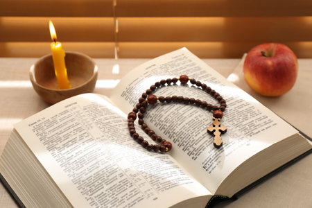 Bible with prayer beads, candle and apple near window indoors. Great Lent seasonの写真素材