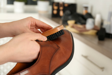 Woman cleaning stylish footwear indoors, closeup. Shoe care accessoriesの写真素材