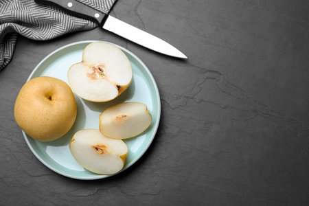 Cut and whole apple pears on black table, flat lay. Space for textの写真素材