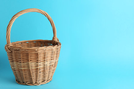 Empty wicker basket on light blue background, space for text. Easter itemの写真素材