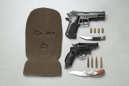 Flat lay composition with balaclava and weapons on white tableの写真素材