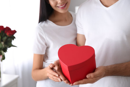 Lovely couple with gift box at home, closeup. Valentine's day celebrationの写真素材