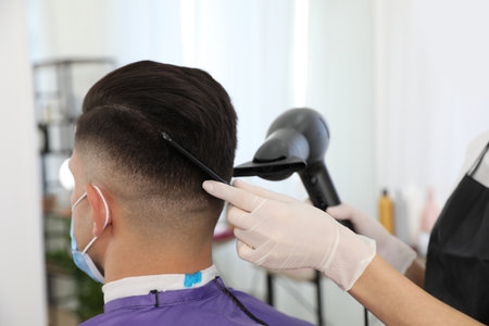 Professional stylist working with client in salon, closeup. Hairdressing services during Coronavirus quarantineの写真素材