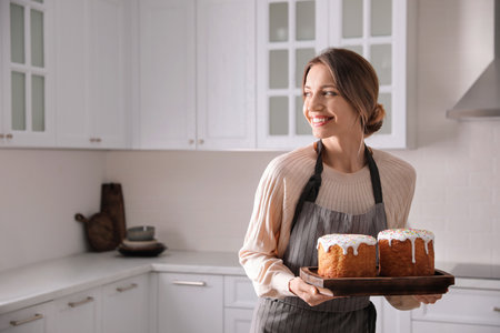 Young woman with traditional Easter cakes in kitchen, space for textの写真素材