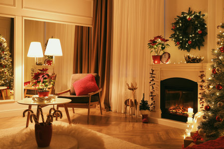 Beautiful living room interior with burning fireplace and Christmas decor in the eveningの写真素材