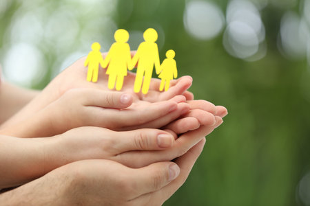 Parents and kid holding paper cutout of family in hands outdoors, closeupの写真素材