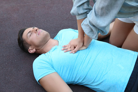Young woman performing CPR on unconscious man outdoors. First aidの写真素材