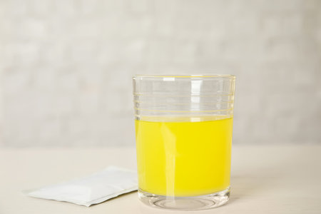 Glass of dissolved medicine and sachet on white wooden tableの写真素材