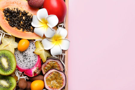 Different tropical fruits in wooden box on pink background, top view. Space for textの写真素材