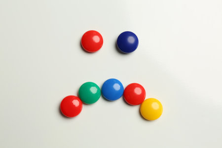 Sad face made with colorful magnets on white background, flat layの写真素材