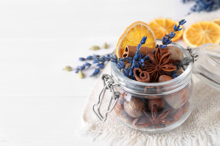 Aromatic potpourri in glass jar on white table, closeup. Space for text