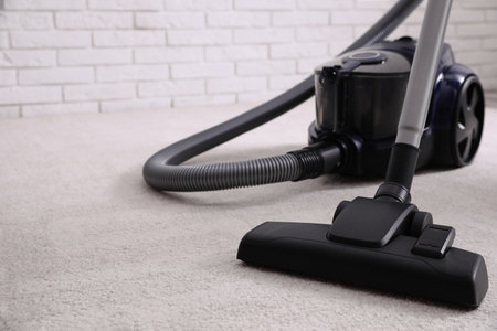 Modern vacuum cleaner on carpet indoors, closeup. Space for textの写真素材