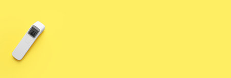 Infrared thermometer on yellow background, top view with space for text. Checking temperature during Covid-19 pandemicの写真素材