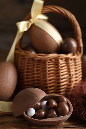 Tasty chocolate egg with candies on wooden table. Space for textの写真素材