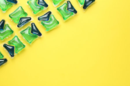 Laundry capsules on yellow background, flat lay. Space for textの写真素材