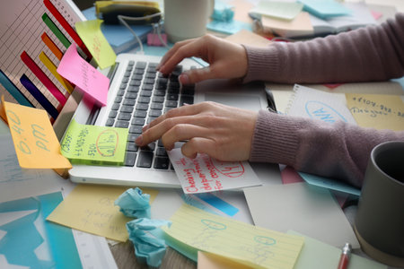 Overwhelmed woman working at messy office desk, closeup