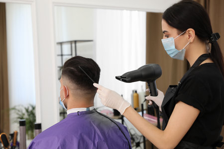 Professional stylist working with client in salon. Hairdressing services during  pandemicの写真素材
