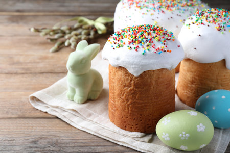 Beautiful Easter cakes with painted eggs and bunny on wooden tableの写真素材