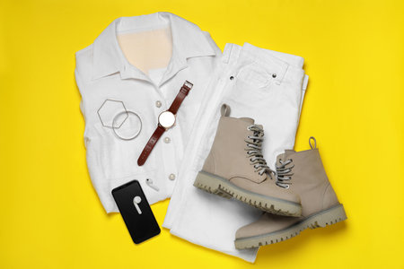Stylish boots, new clothes, smartphone and accessories on yellow background, flat layの写真素材