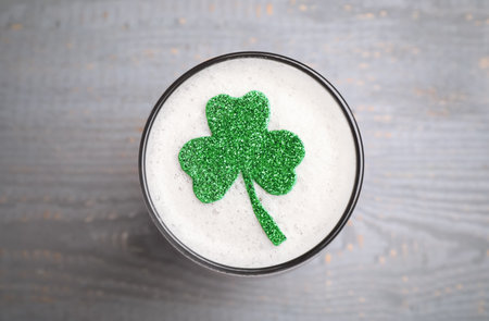 Glass of beer with clover leaf on gray wooden table, top view. St Patrick's Day celebrationの写真素材