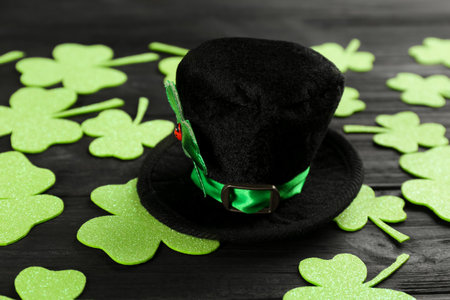 Leprechaun's hat and decorative clover leaves on black wooden background. St. Patrick's day celebrationの写真素材