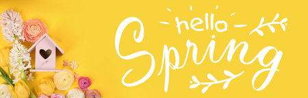 Hello Spring. Wooden bird house and fresh flowers on yellow background, flat layの写真素材