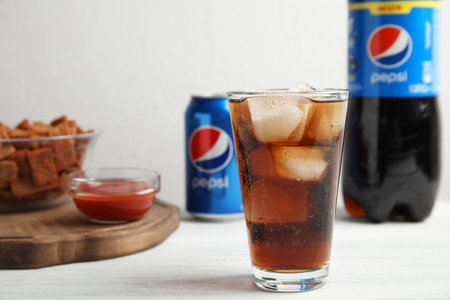 MYKOLAIV, UKRAINE - FEBRUARY 15, 2021: Glass of Pepsi and snack on white wooden table, space for textのeditorial素材